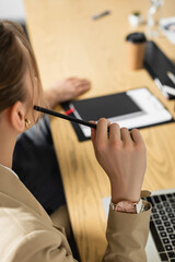 partial view of young businesswoman holding pen in conference room, blurred background