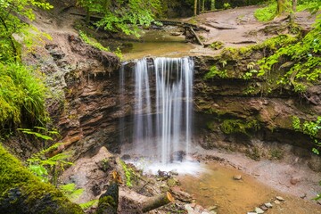 Germany, Mystical tropical waterfall in green forest nature landscape while rain near murrhardt in...