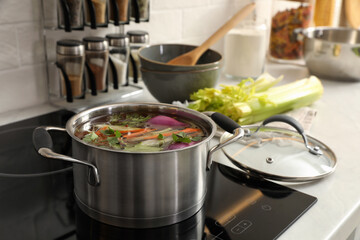 Pot of delicious vegetable bouillon on stove in kitchen