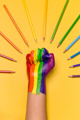 Photo of a raised fist colored with the rainbow color for lgbtq community.