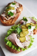 Cold baked pork, pickle and lettuce with remoulade (danish tartar sauce) Smorrebrod. Danish open faced sandwich. Selective focus