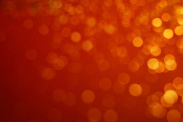 Blurred view of golden lights on red background. Bokeh effect