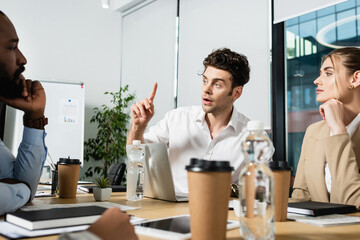 young businessman showing idea sign during meeting with interracial colleagues