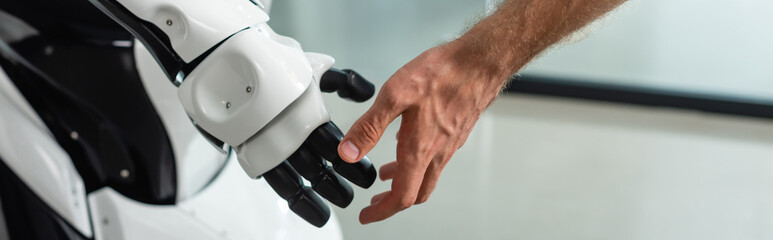 partial view of engineer touching hand of humanoid robot, banner