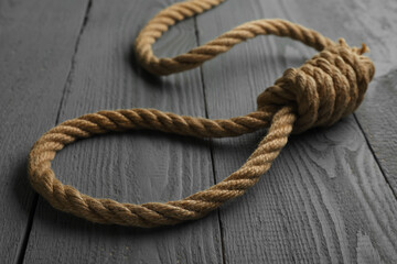 Rope noose on grey wooden table, closeup