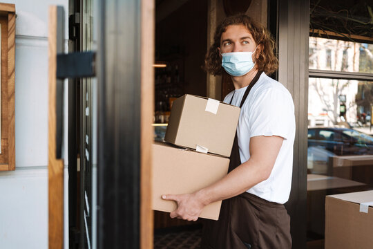 Young White Cafe Worker In Face Mask Taking Delivery Outdoors