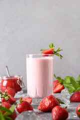 Indian strawberry lassi or milkshake on gray background. Vertical format. Traditional ayurvedic healthy drink with strawberries of yogurt, fruits and ice cube.
