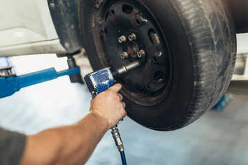 Mechanician changing car wheel in auto repair shop