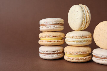 Pile of delicious colorful macarons on brown background. Space for text