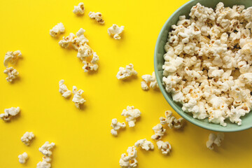Delicious popcorn in bowl and on yellow background close-up. Food and snack concept.