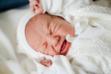crying Newborn baby sleeps in white clothes. attire for discharge from hospital.