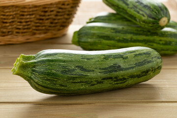 Single fresh raw green spotted courgette on a cuttingboard close up  