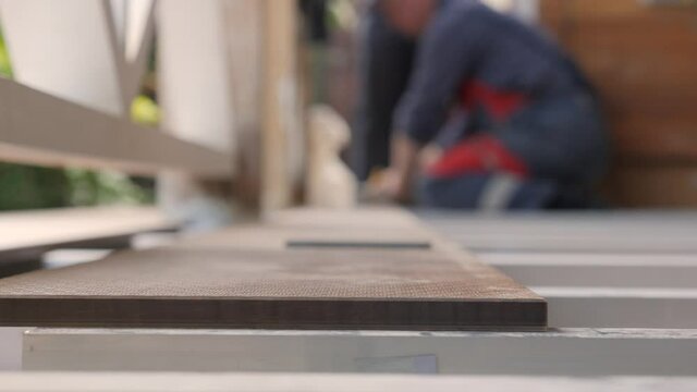 Flooring installation a terrace. Carpenter draws a cutting line on wood plank. Close up measuring floorboards with corner ruler. Joiner with pencil and meter marks measure on wooden board. Repair home