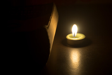 Candle or taper with old book or bible isolated on black background with concept of religious vintage belief photo in the home, resedence or accommodation