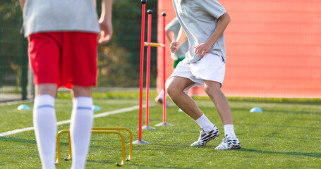 Teenage Football Players on Training Camp. Young Boys Running Slalom Track Between Training Poles and Jumping Over Hurdles. Soccer Training Equipment