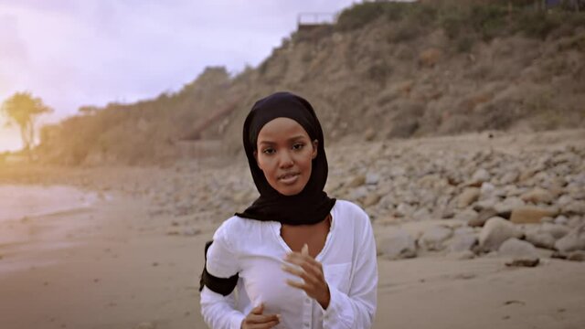 Somali-American woman jogging on the beach in Malibu at sunset.