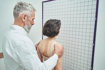 Doctor assessing the spinal alignment from a posterior view