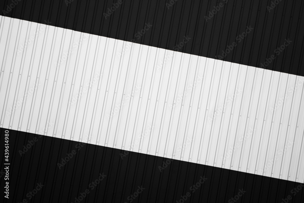 Wall mural Black and white corrugated iron sheet used as a facade of a warehouse or factory. Texture of a seamless corrugated zinc sheet metal aluminum facade. Architecture. Metal texture.