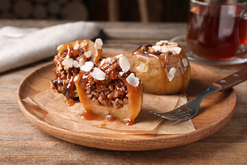 Delicious baked apples with nuts and caramel served on wooden table