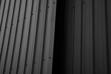 Black corrugated iron sheet used as a facade of a warehouse or factory. Texture of a seamless corrugated zinc sheet metal aluminum facade. Architecture. Metal texture.