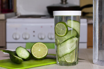 Cucumber and lime slices are filled with water in a glass. Cooking water infused with lime and...