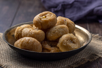 Indian traditional sweet balushahi served on a metal plate on wooden background
