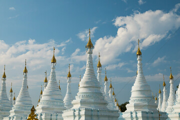 Fototapeta premium Cityscape of clouds and white Buddhist stupas in Sanda Muni Pagoda, memorial to Mindon Min's in Mandalay, Myanmar