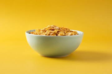 Corn flakes in a blue bowl on yellow background