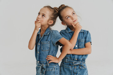 Blonde two girls dressed overalls thinking and looking opposite sides