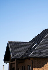 Fototapeta premium Brown corrugated metal profile roof installed on a modern house. The roof of corrugated sheet. Roofing of metal profile wavy shape. Modern roof made of metal. Metal roofing.