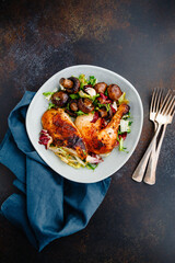Roasted chicken leg and breast with fresh salad and champignons on a plate.
