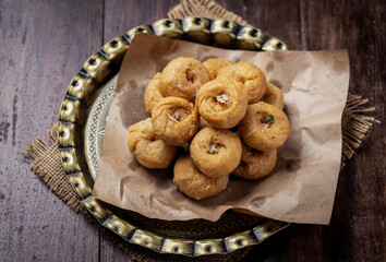 Indian traditional sweet balushahi served on a metal plate on wooden background