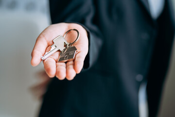 close up view of hand businesswomen giving keys to an apartment or home to buyer, renter, leasing house agent, owner new home, real estate business concept.