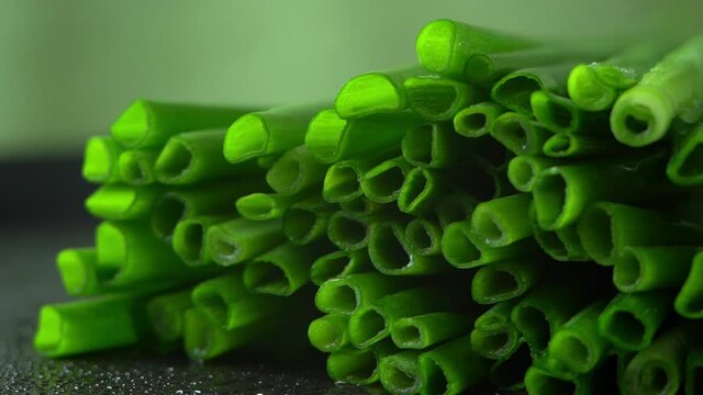 Close up of fresh cut green onions with water drops rotate on black tray. Healthy and organic vegetables concept. Greens. Harvest, crop. Macro food background