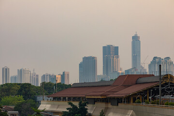 Fototapeta premium The Gondangdia train station, and the cityscape of Jakarta skyscrapers in the background at sunset