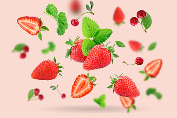 Strawberry berries and cherry berries levitating on a pink background. Horizontal. Selective focus.