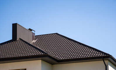 Brown corrugated metal profile roof installed on a modern house. The roof of corrugated sheet. Roofing of metal profile wavy shape. Modern roof made of metal. Metal roofing.