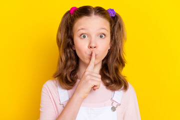 Fototapeta premium Portrait of attractive trendy amazed brown-haired girl showing shh sign taboo isolated over bright yellow color background