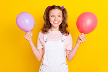 Portrait of attractive cheerful girl holding balls decor festal event organization isolated over bright yellow color background