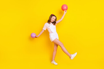 Full length body size view of pretty cheerful girl holding air balls dancing havin fun free time isolated over bright yellow color background