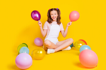 Full length body size photo schoolgirl at party keeping colorful balloons smiling isolated vibrant...