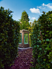 A lantern that stands between hedges