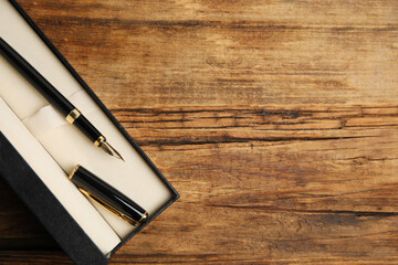 Beautiful fountain pen in box on wooden table, top view. Space for text