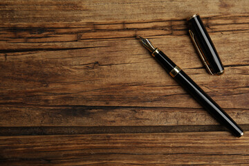 Beautiful fountain pen on wooden table, flat lay. Space for text