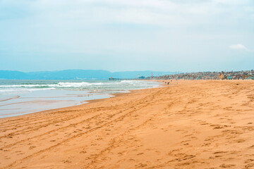Early morning sunrise and soft haze on Manhattan Beach, waves and rescue towers, Los Angeles. Los Angeles, USA - 14 Apr 2021