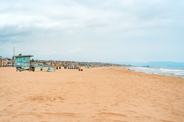 Early morning sunrise and soft haze on Manhattan Beach, waves and rescue towers, Los Angeles. Los Angeles, USA - 14 Apr 2021