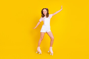 Fototapeta na wymiar Full length body size view of attractive cheerful girl riding rollers having fun isolated over bright yellow color background