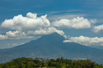 View of Klabat volcano, the highest volcano in Sulawesi, and the surrounding rainforest landscape, wrapped in white clouds, Indonesia