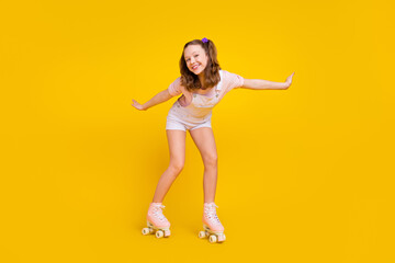 Full length body size photo schoolgirl riding rollers in summer isolated bright yellow color background