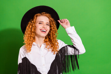 Portrait of attractive cheerful wavy-haired girl touching hat laughing isolated over bright green...